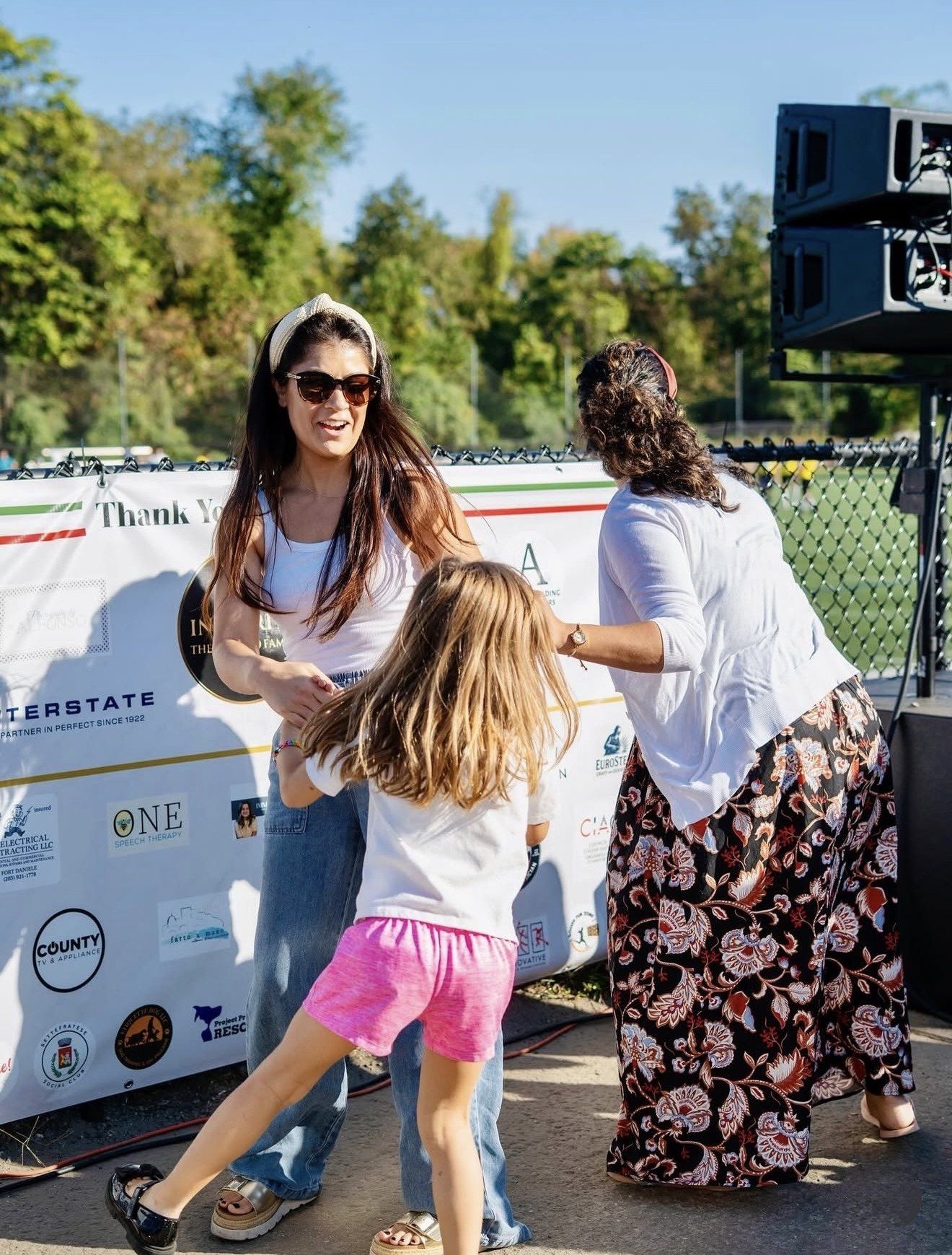 Young supporters in team jerseys watching from the fence at the Stamford Italian Soccer League Finals