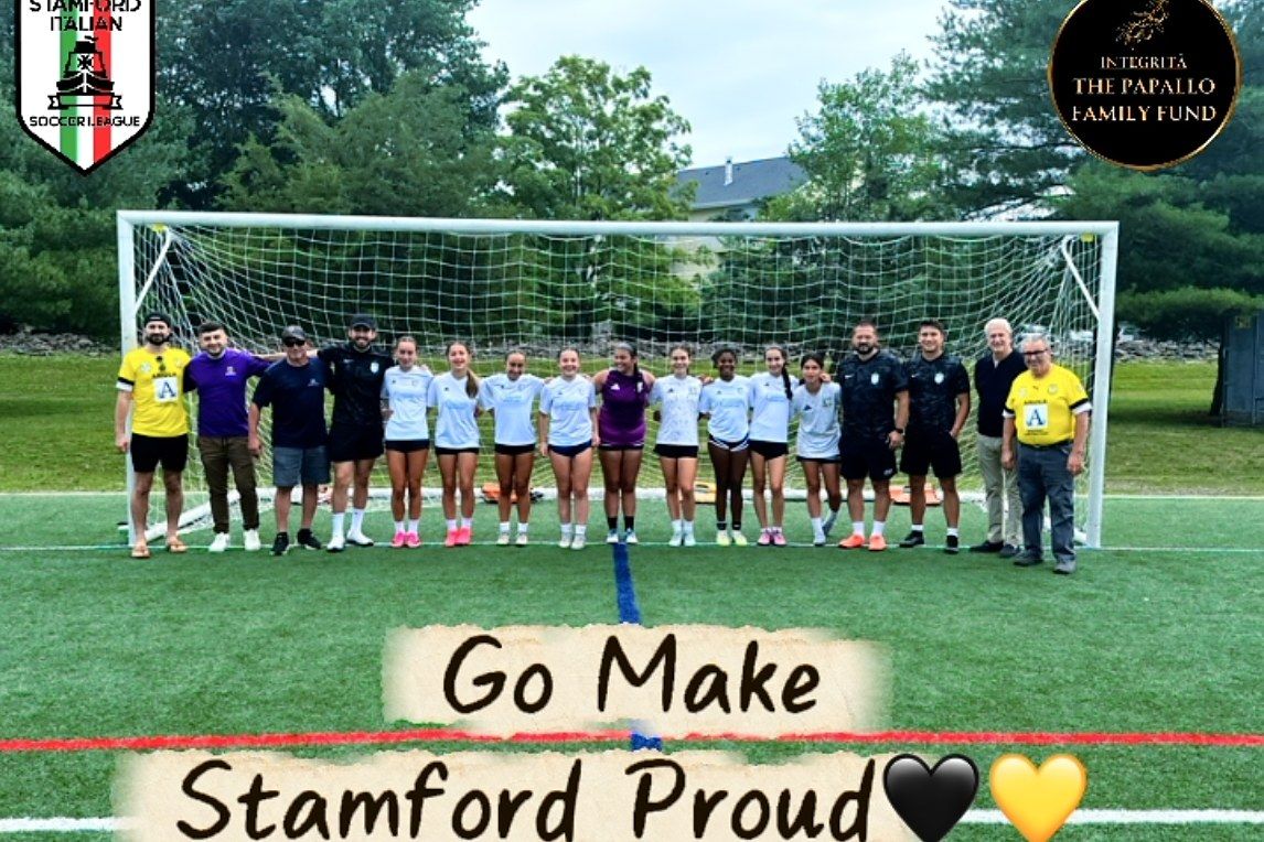 Players and coaches lined up at the goal beneath Stamford Italian Soccer League banners